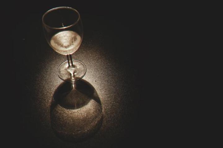 Photo of an empty wine glass under a low-light spotlight with a black background.